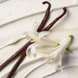 Vanilla beans and vanilla flower on a light wooden surface