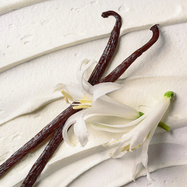 Vanilla beans and vanilla flower on a light wooden surface