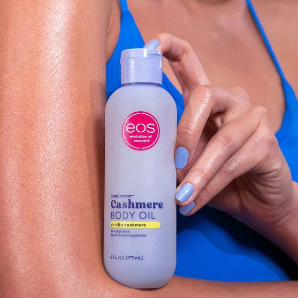 Person holding a bottle of eos Cashmere Body Oil on a blurred background