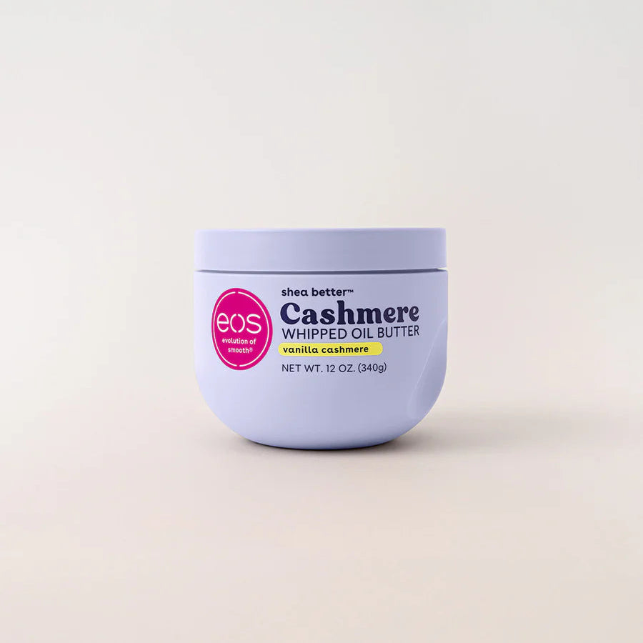 A 12 oz jar of EOS Cashmere Whipped Oil Butter in vanilla cashmere, featuring a light lavender-purple container with a pink circular logo and black text, set against a clean off-white background.